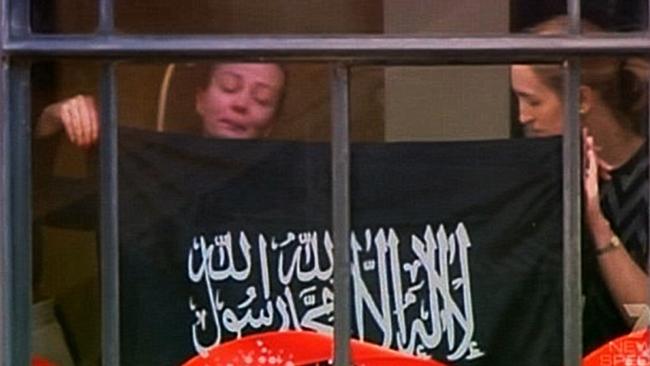 Hostages Marcia Mikhael (left) and Katrina Dawson were forced to hold up a flag during the siege