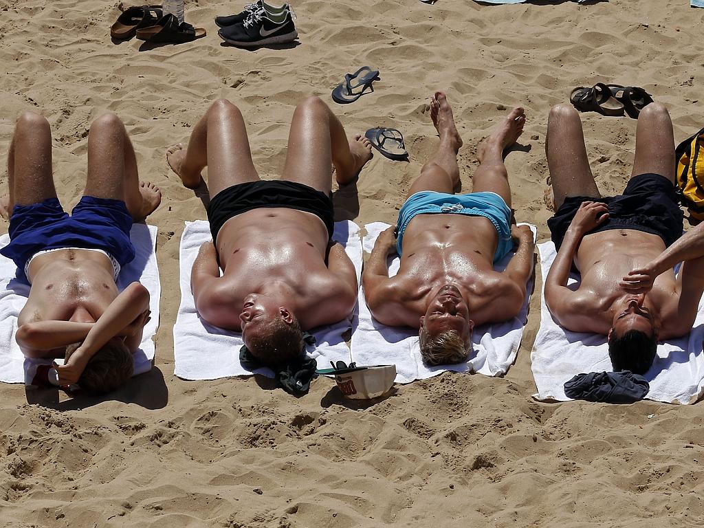 Four men sunbathe on a beach of the tourist village of Cascais on the outskirts of Lisbon on June 29, 2015. Picture: AFP