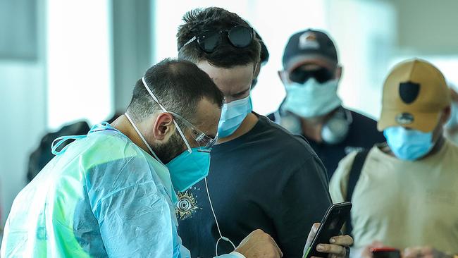 COVID-19 Enforcement and Compliance Officers check travellers documents as they arrive at Melbourne Airport from Brisbane. Picture: NCA NewsWire / Ian Currie