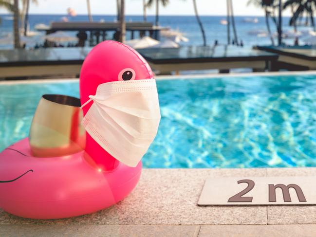 Inflatable pool toys at tropical resort pool wearing face masks staying 2 meters aside to keep social distance during COVID-19 pandemic. Concept of travel industry difficulties during summer 2020credit: iStockescape 14 marchkendall hill