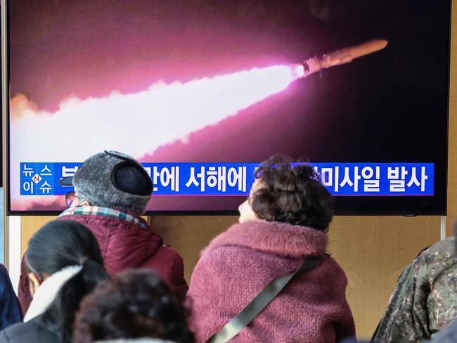 People watch a television screen showing a news broadcast with file footage of a North Korean missile test, at a railway station in Seoul. Picture: AFP