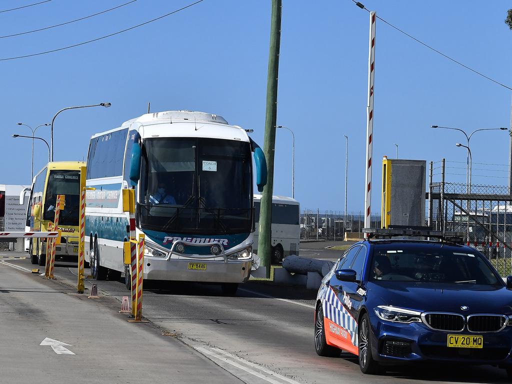 A police car escorts buses carrying crew members of the Ruby Princess cruise liner out of Port Kembla, south of Sydney, today. Picture: Saeed Khan/AFP