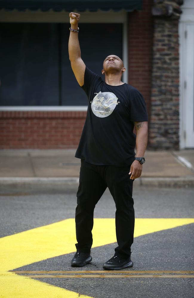 Ronald Stewart raises his fist while standing over the phrase "Black Lives Matter" painted on the street near the corner of Archer Street and Greenwood Avenue in Tulsa. Picture: AP