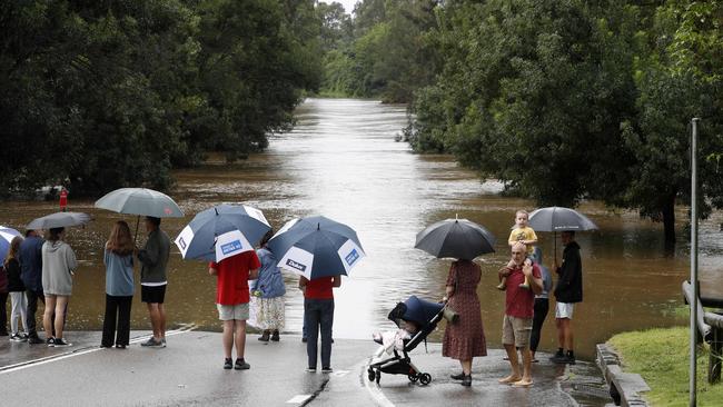 Locals assessing the flooded Hawkesbury River in North Richmond as the flood cuts them off from Greater Sydney. Picture: Jonathan Ng