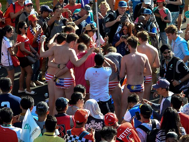 This picture taken on October 2, 2016, shows spectators with swimwear bearing a Malaysian flag posing for pictures during the Formula One Malaysian Grand Prix in Sepang / AFP