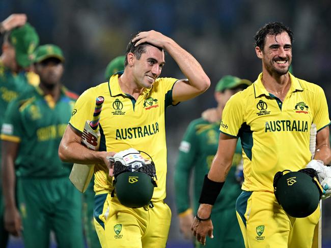 Australia's captain Pat Cummins (C) and Mitchell Starc (R) walk back to the pavilion after their win at the end of the 2023 ICC Men's Cricket World Cup one-day international (ODI) second semi-final match against South Africa at the Eden Gardens in Kolkata on November 16, 2023. (Photo by DIBYANGSHU SARKAR / AFP) / -- IMAGE RESTRICTED TO EDITORIAL USE - STRICTLY NO COMMERCIAL USE --