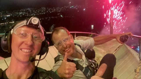 Dean Jakubowski, right, perched on top of the Opera House as the annual fireworks launch into the sky. Picture: Sydney Opera House