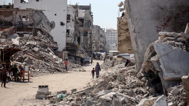 Palestinians walk near destroyed buildings after more than a year of Israeli strikes on Gaza.