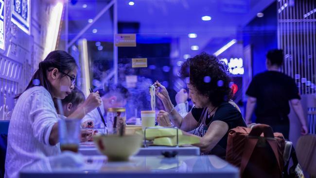 People eat at a Hong Kong restaurant with perspex shields between tables. Picture: AFP