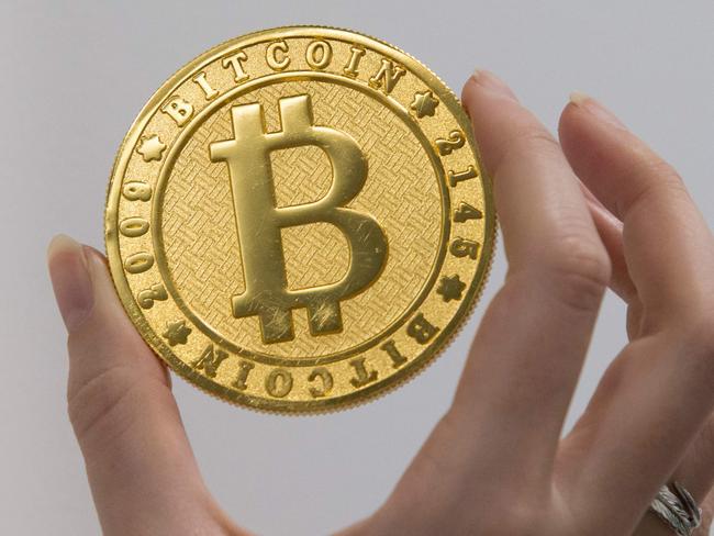 A person holds on January 17, 2018 shows a visual representation of the digital cryptocurrency Bitcoin, at La Maison du Bitcoin in Paris. / AFP PHOTO / GEOFFROY VAN DER HASSELT