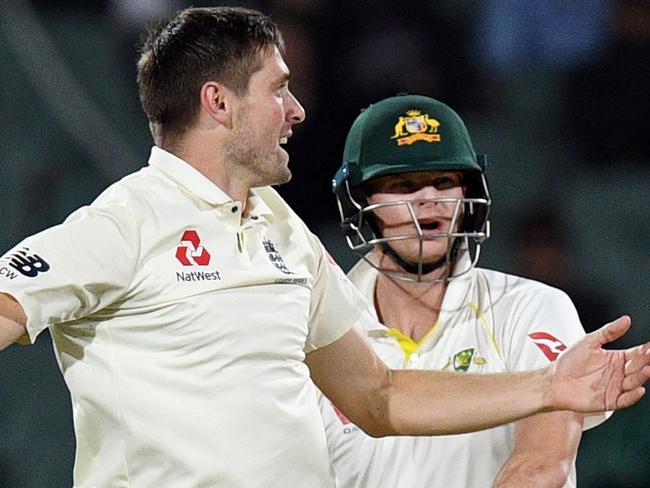 England's paceman Chris Woakes (L) celebrates dismissing Australia's batsman Steve Smith on the third day of the second Ashes cricket Test match in Adelaide in December 4, 2017. / AFP PHOTO / William WEST / -- IMAGE RESTRICTED TO EDITORIAL USE - STRICTLY NO COMMERCIAL USE --