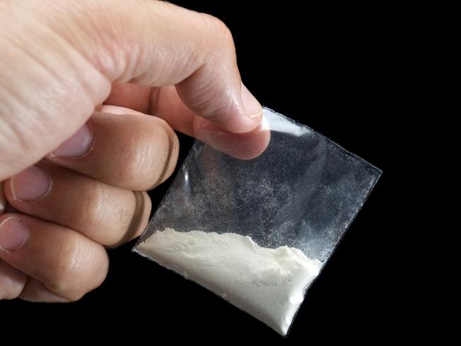 Generic photo of cocaine. Dealer is holding drug bag in his hand on a black background. Picture: iStock