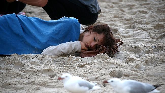 A sleepy reveller takes a nap on Surfers Paradise beach. Pic by David Clark