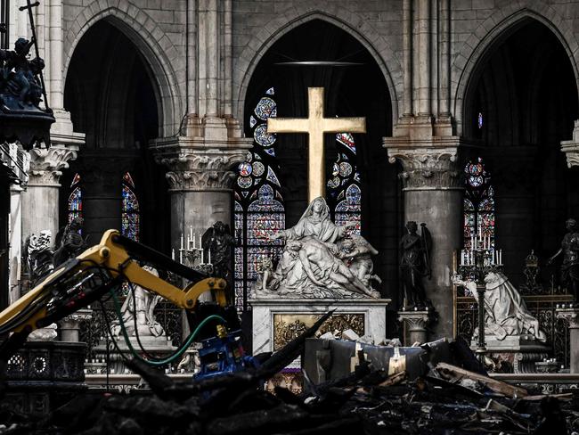 A picture shows rubble and the cross at the altar inside the the Notre Dame de Paris Cathedral after it sustained major fire damage the previous month, during a visit by the Canadian prime minister in Paris on May 15, 2019. - The April 15, fire destroyed the roof and steeple of the 850-year-old Gothic cathedral. Images of the ancient cathedral going up in flames sparked shock and dismay across the globe as well as in France, where it is considered one of the nation's most beloved landmarks. (Photo by Philippe LOPEZ / POOL / AFP)