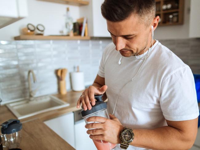 Young man making protein shake before training