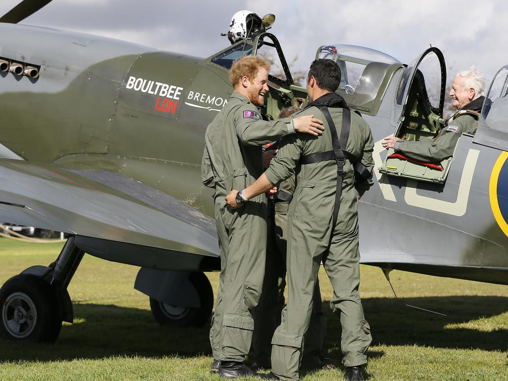 Britain’s Prince Harry hugs Nathan Forster as veteran Tom Neill sits in the cockpit of a Spitfire after a Battle of Britain display at Goodwood Aerodrome in West Sussex, England. Picture: AP