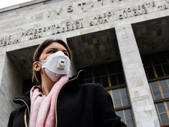 A woman wearing a respiratory mask exits from the Palace of Justice in Milan. Picture: AFP