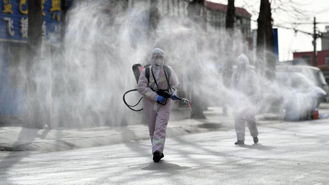 People in protective suits spray disinfectant on a street in Shijiazhuang, in northern China's Hebei province. Picture: AFP