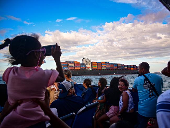 Tourists look at a cargo ship waiting to enter the Panama Canal in Panama City on January 25, 2025. Panama has complained to the United Nations over US President Donald Trump's "worrying" threat to seize the Panama Canal, even as it launched an audit of the Hong Kong-linked operator of two ports on the interoceanic waterway. (Photo by MARTIN BERNETTI / AFP)