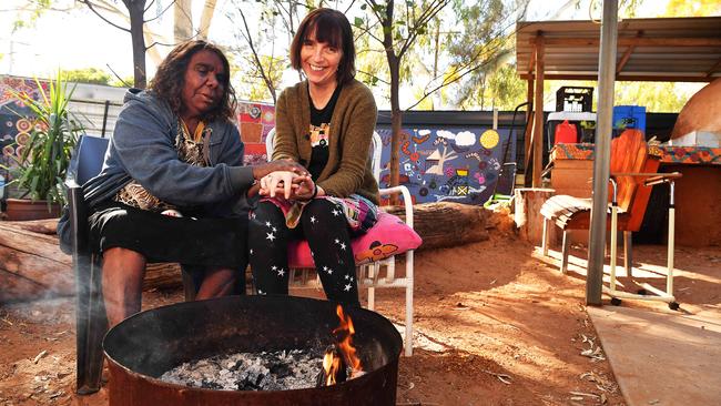 Marlene Spencer Nambidjima, from Kintore, 540km west of Alice Springs, warms her hands with remote area nurse Sarah Brown AM. Picture: Chloe Erlich