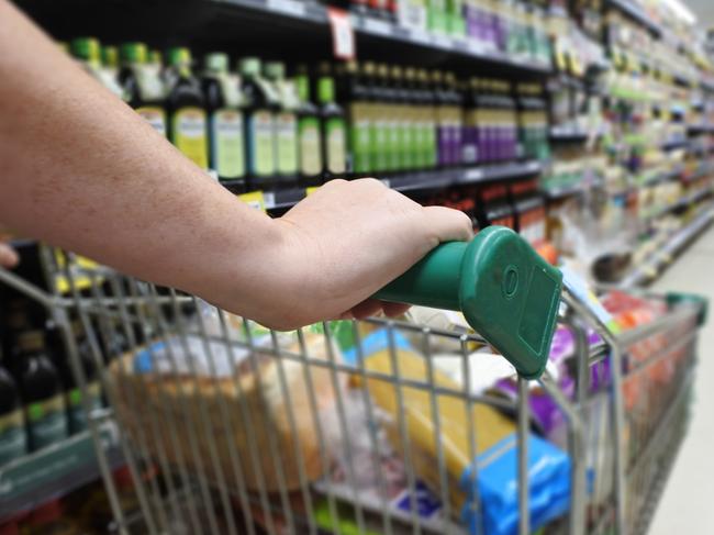 Woman hands pushing a shopping trolley in a supermarket.