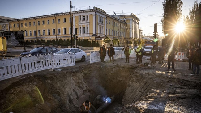 Workmen fix a pipe in the crater left by a Russian missile strike near Taras Shevchenko National University in Kyiv on Monday. Nineteen people were killed by the strikes across Ukraine. Picture: Getty Images