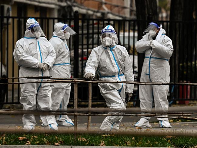 TOPSHOT - Health workers are seen along a street near a residential area under lockdown due to Covid-19 coronavirus restrictions in Beijing on November 24, 2022. (Photo by Noel CELIS / AFP)