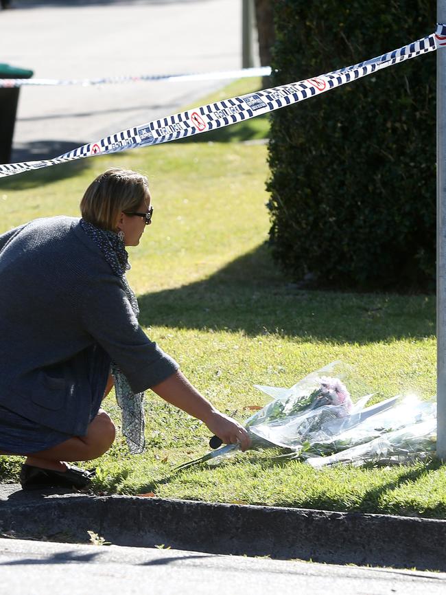 Locals lay flowers at the front yard of the Davidson home where a family was found dead. Picture: John Grainger