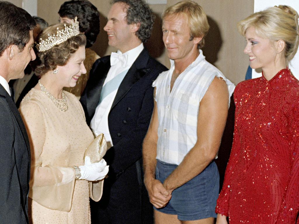 <b>1980 – Sydney</b> On May 27, 1980, the Queen and Prince Philip attended an all-Australian Royal Charity Concert at the Sydney Opera House that was televised nationally and featured stars including Paul Hogan and Olivia Newton-John, both pictured, Peter Allen, John Farnham, Helen Reddy and Bert Newton. Newton later recalled that Allen “did his first public performance of <i>I Still Call Australia Home</i> as the finale … it was just electric, he walked away with the audience”. Picture: National Archives