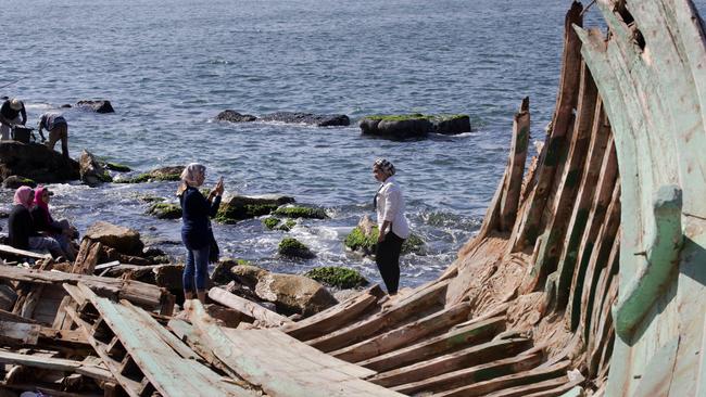 Egyptians pose for pictures next to ribs of an old boat on the beachfront in Alexandria, Egypt. Picture: AP Photo/Amr Nabil