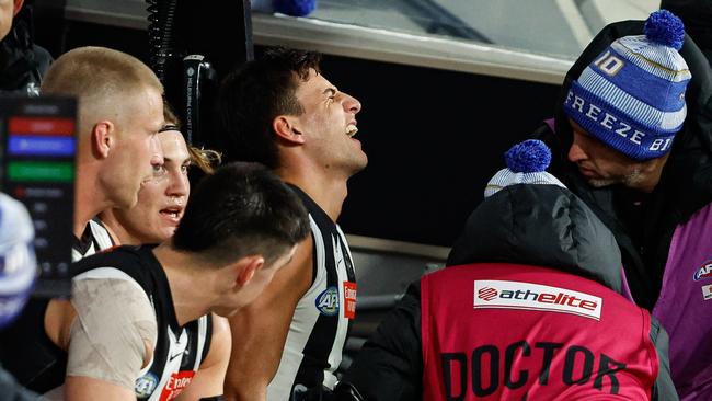 MELBOURNE, AUSTRALIA - JUNE 10: Nick Daicos of the Magpies is assessed by medical staff on the bench during the 2024 AFL Round 13 match between the Collingwood Magpies and the Melbourne Demons at The Melbourne Cricket Ground on June 10, 2024 in Melbourne, Australia. (Photo by Dylan Burns/AFL Photos via Getty Images)