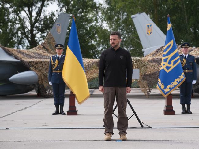 UNSPECIFIED, UKRAINE - AUGUST 4: President of Ukraine Volodymyr Zelenskyi stands in front of the first General Dynamics F-16 Fighting Falcons received by Ukraine as he congratulates Ukrainian military on the Day of Ukrainian Air Force on August 4, 2024 in Unspecified, Ukraine. At the event for the Day of Ukrainian Air Force with the participation of President of Ukraine Volodymyr Zelenskyi, the first General Dynamics F-16 Fighting Falcons received by Ukraine were demonstrated. (Photo by Vitalii Nosach/Global Images Ukraine via Getty Images)