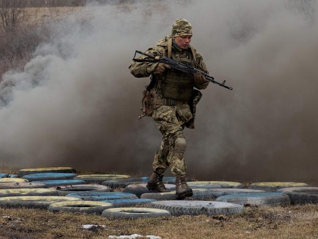 A Ukrainian female military serviceman of the 24th Mechanized Brigade runs with a rifle across an obstacle course made with tyres as she takes part in a training drill at an undisclosed location in the eastern region of Ukraine on March 4, 2025, amid the Russian invasion of Ukraine. (Photo by Tetiana DZHAFAROVA / AFP)