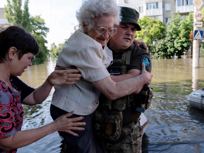 A Ukrainian serviceman help local residents during an evacuation from a flooded area in Kherson on June 7, 2023, following damages sustained at Kakhovka hydroelectric power plant dam. Ukraine was evacuating thousands of people on June 7 after an attack on a major Russian-held dam unleashed a torrent of water, inundating two dozen villages and sparking fears of a humanitarian disaster. (Photo by ALEKSEY FILIPPOV / AFP)