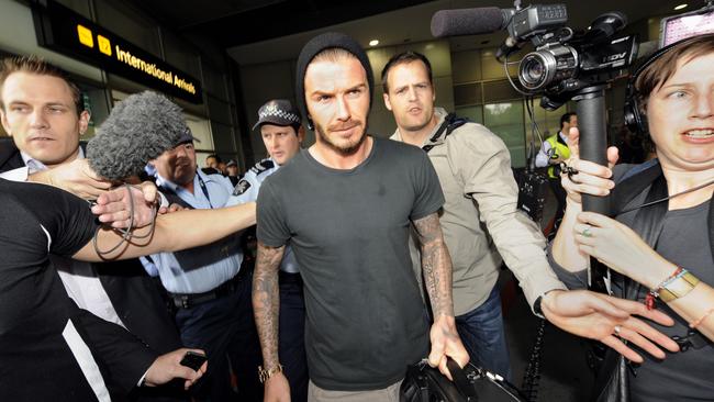 David Beckham surrounded by a throng of security and media on arrival at Melbourne Airport.