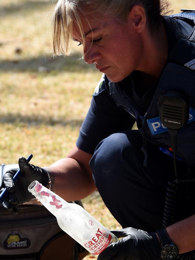 Police inspect a bottle found near the rubbish bin in Catani Gardens. Picture: Nicole Garmston