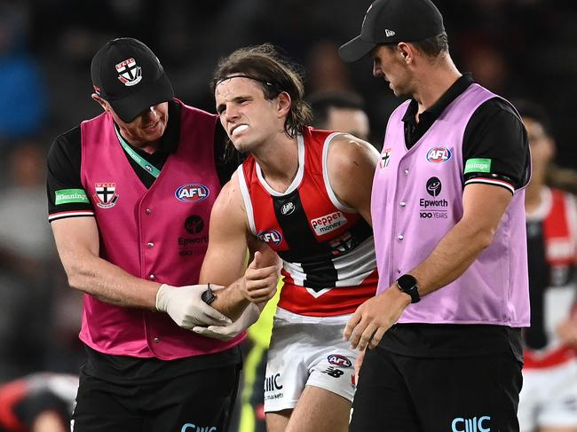 MELBOURNE, AUSTRALIA - MARCH 05: Hunter Clark of the Saints is helped from the ground by trainers during the AFL AAMI Community Series match between the Essendon Bombers and the St Kilda Saints at Marvel Stadium on March 05, 2022 in Melbourne, Australia. (Photo by Quinn Rooney/Getty Images)