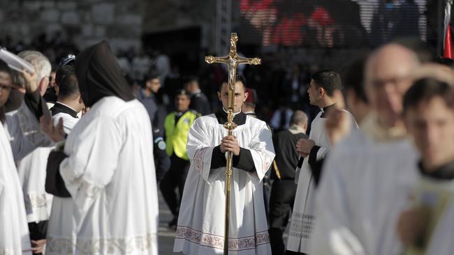 Pilgrimage ... A clergyman holds a crucifix in Manger Square outside the Church of the Nativity. Thousands of Palestinians and tourists flocked into the West Bank city of Bethlehem to mark Christmas in the "little town" where many believe Jesus Christ was born. Picture: AFP PHOTO/AHMAD GHARABLI
