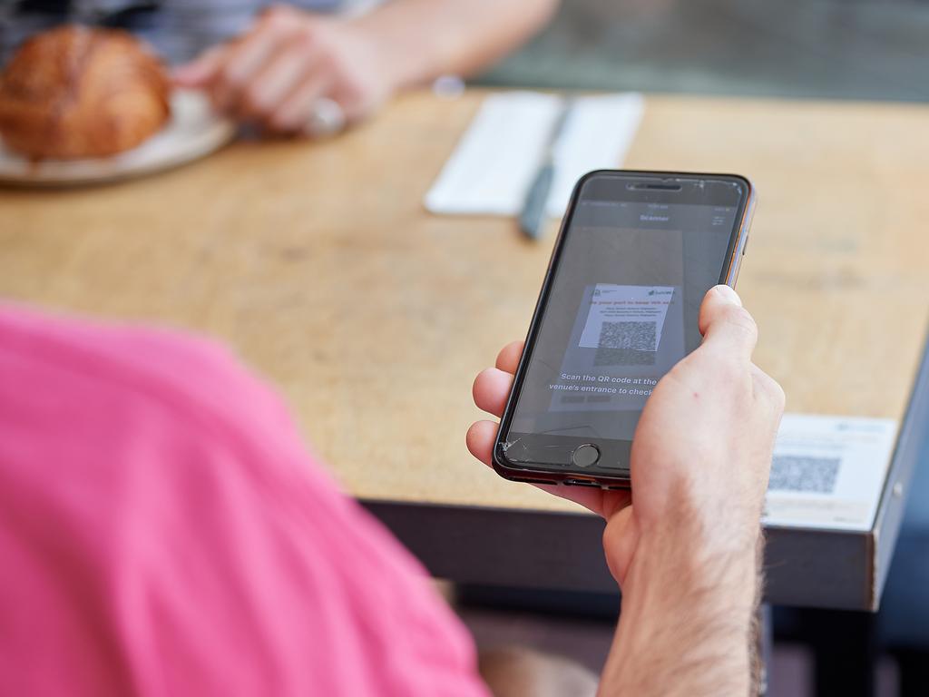 A cafe guest scans a QR code for COVID-19 contact tracing. (Photo by Stefan Gosatti/Getty Images)