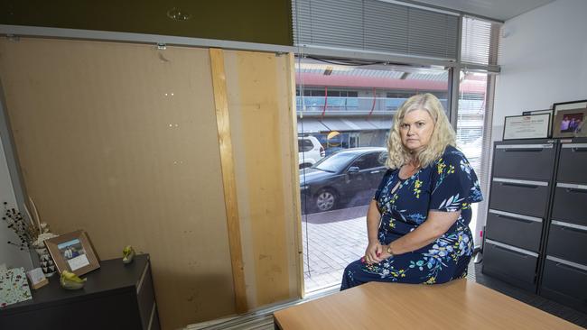 Alice Springs Mortgage Broker Angelique Glasson from Territory Loans with the boarded up window of her office. Picture: Mark Brake