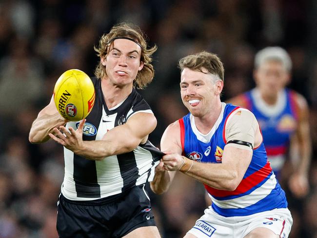 MELBOURNE, AUSTRALIA - MAY 31: Harvey Harrison of the Magpies handpasses the ball as he's tackled by Lachlan Bramble of the Bulldogs during the 2024 AFL Round 12 match between the Collingwood Magpies and the Adelaide Crows at The Melbourne Cricket Ground on May 31, 2024 in Melbourne, Australia. (Photo by Dylan Burns/AFL Photos via Getty Images)