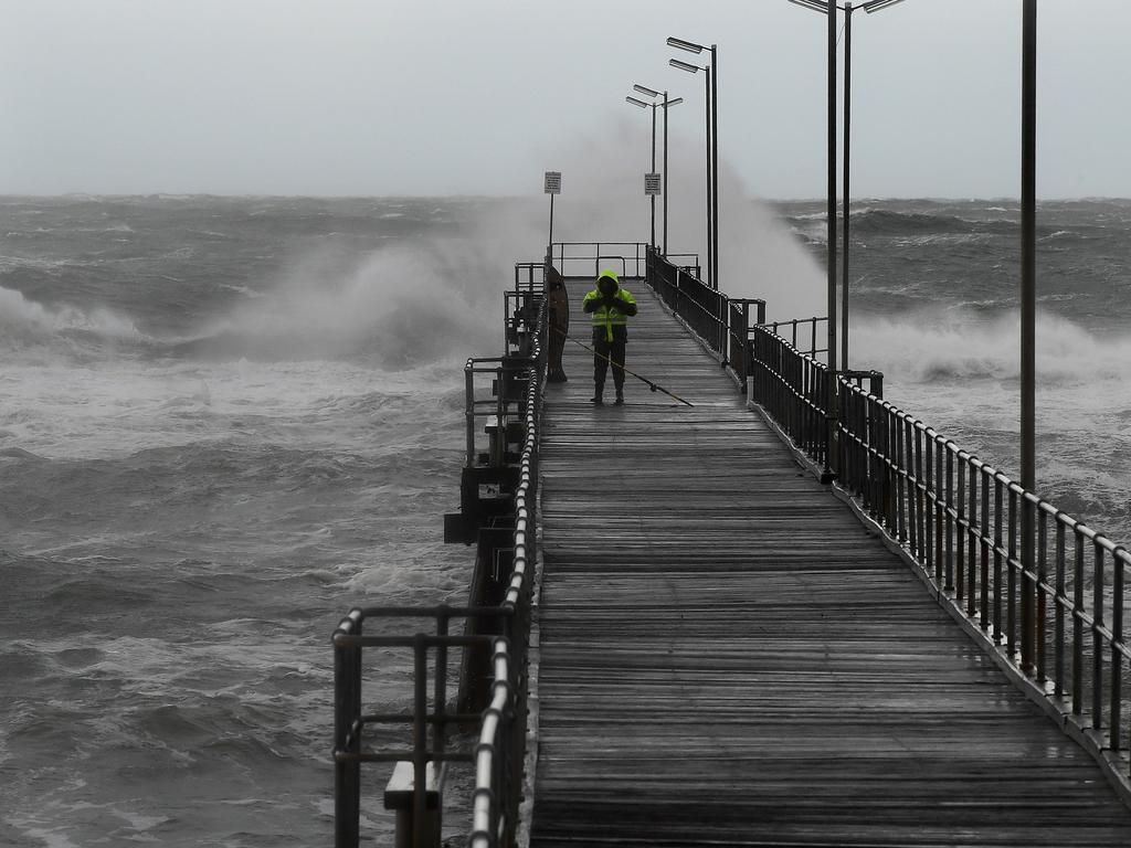 A solitary fisherman braves the waves at the Port Noarlunga jetty. Picture: Campbell Brodie