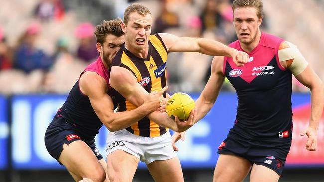 Tom Mitchell handballs while being tackled by Jack Viney.