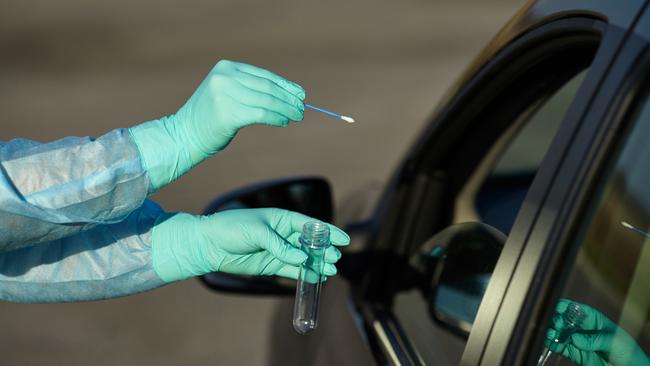 Epidemic concept COVID-19. Coronavirus Test Station. Medical worker in full protective gear takes sample from patient at a COVID-19 drive-thru test site. Testing is done by throat swab.