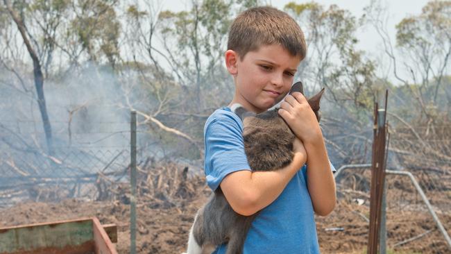 Wyatt Dobie, 9, hugs his cat Milo after returning to his home in Sarina Beach on Thursday morning. Residents in the area were evacuated in the early hours when a fire came dangerously close to homes.