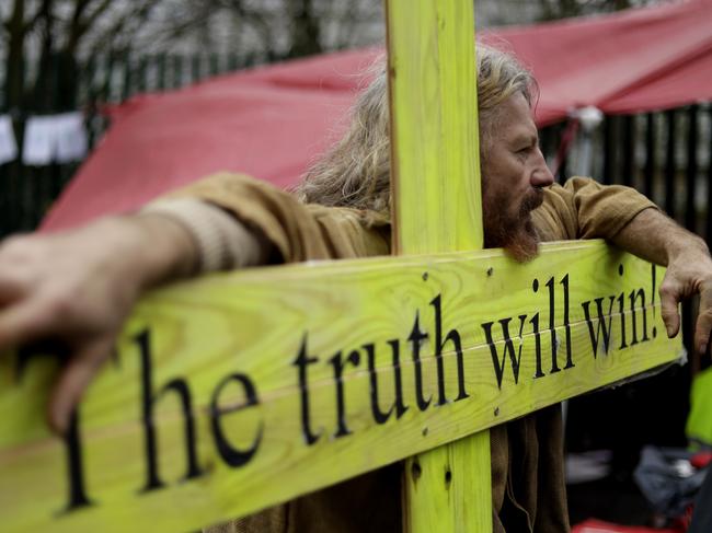 A supporter leans on a wooden cross as he protests against the extradition of Wikileaks founder Julian Assange outside Belmarsh Magistrates Court in London. Picture: AP Photo