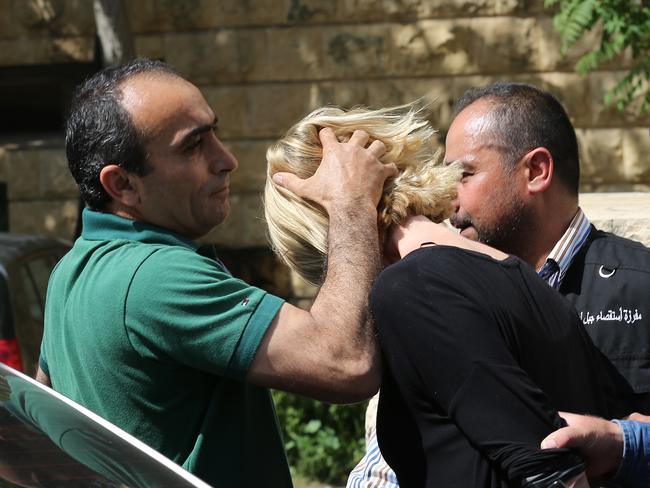 A plainclothes policeman prevents her from looking towards waiting journalists. Picture: AP Photo/Hussein Malla.