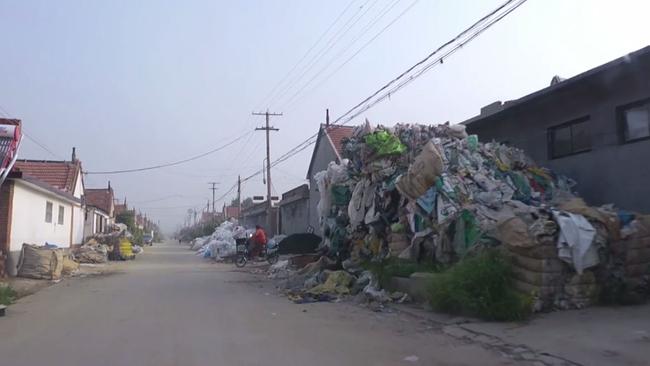 Building high towers of plastic waste, waiting to be recycled, line the town’s streets.