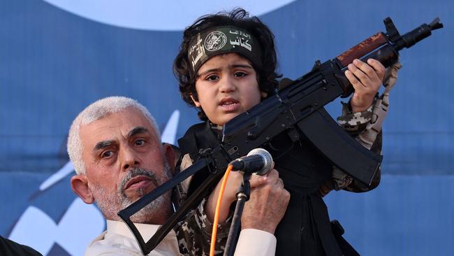 (FILES) Hamas leader Yahya Sinwar holds the child of an Al-Qassam Brigades fighter, who was killed in the recent fighting with Israel, with a Kalashnikov rifle in his hand during a rally in Gaza City on May 24, 2021. An Israeli security official told AFP on October 17, 2024 that the military was conducting a DNA test on a militant's body to confirm whether it was Hamas chief Yahya Sinwar. (Photo by Emmanuel DUNAND / AFP)