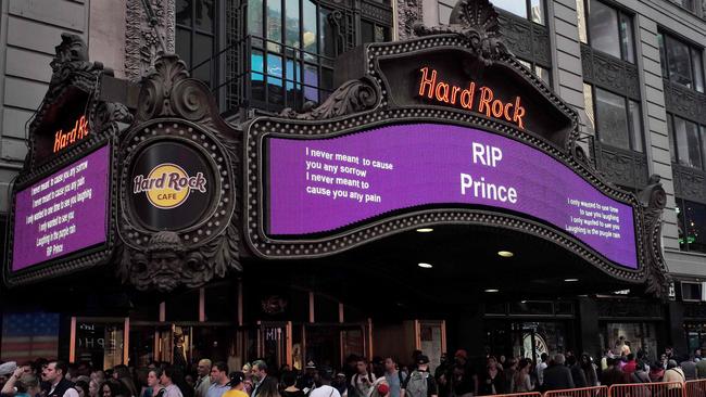 People walk past a "Rest In Peace" message for singer Prince, on an electronic board at the Hard Rock Cafe in New York. Picture: AFP